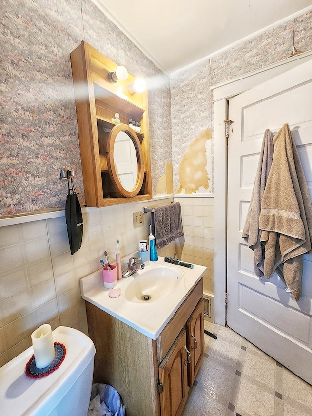 bathroom with vanity, toilet, and tile walls