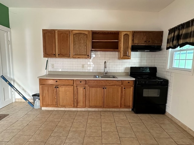 kitchen featuring backsplash, light tile patterned floors, sink, and black gas range oven