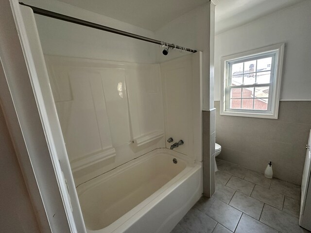 bathroom with shower / bathtub combination, tile patterned floors, toilet, and tile walls