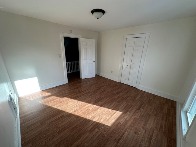 unfurnished bedroom with dark hardwood / wood-style floors and a closet