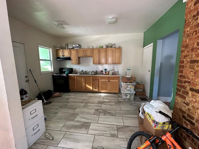 kitchen with sink, black gas range, and decorative backsplash