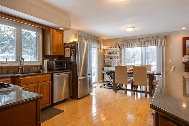 kitchen featuring stainless steel appliances, sink, light hardwood / wood-style flooring, and backsplash