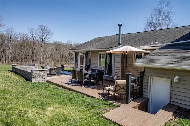 back of property with a wooden deck and a lawn