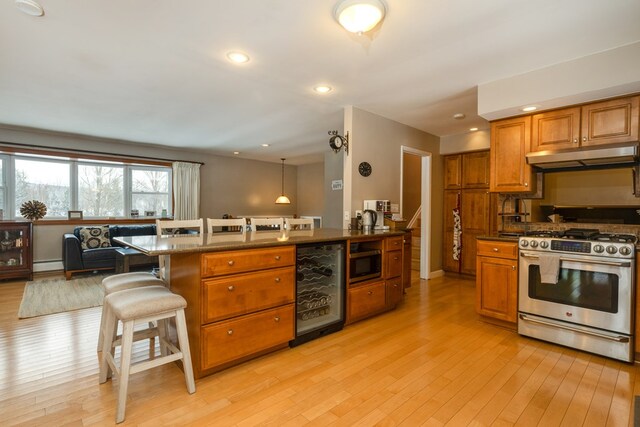 kitchen featuring wine cooler, decorative light fixtures, appliances with stainless steel finishes, a kitchen breakfast bar, and light hardwood / wood-style floors