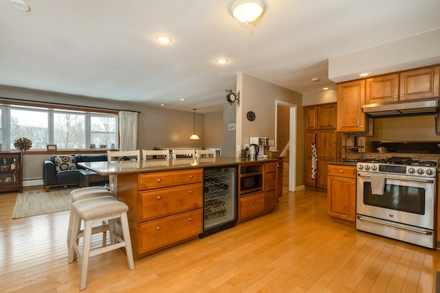 kitchen featuring pendant lighting, light hardwood / wood-style flooring, appliances with stainless steel finishes, a kitchen bar, and beverage cooler