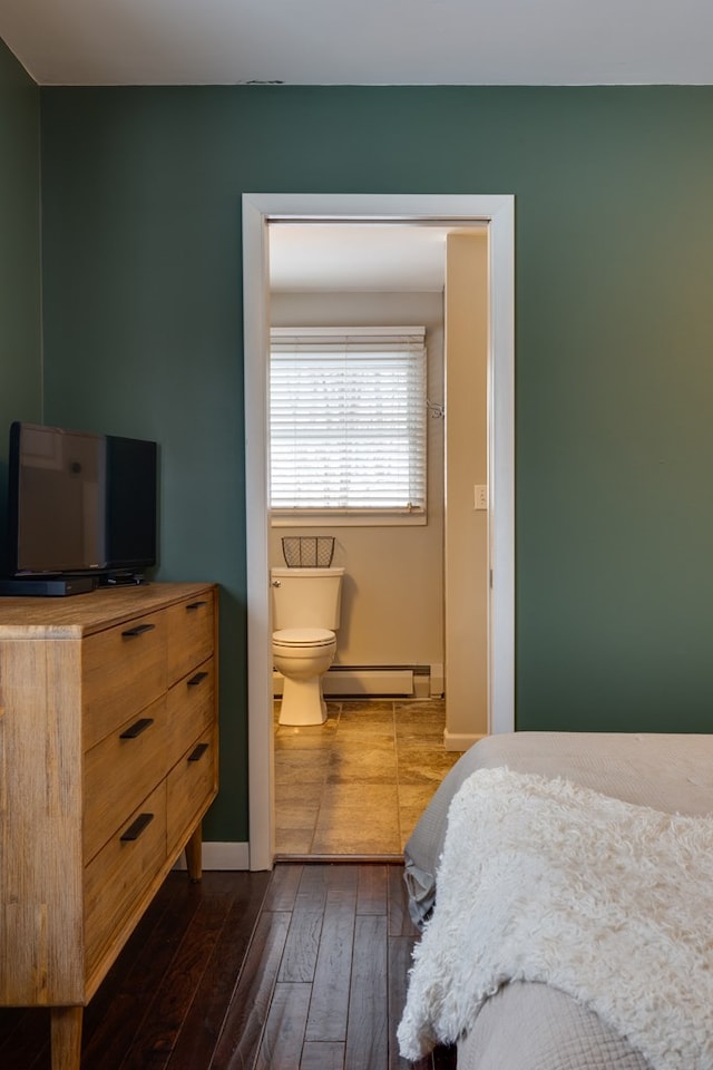 bedroom with dark hardwood / wood-style floors, ensuite bath, and a baseboard radiator