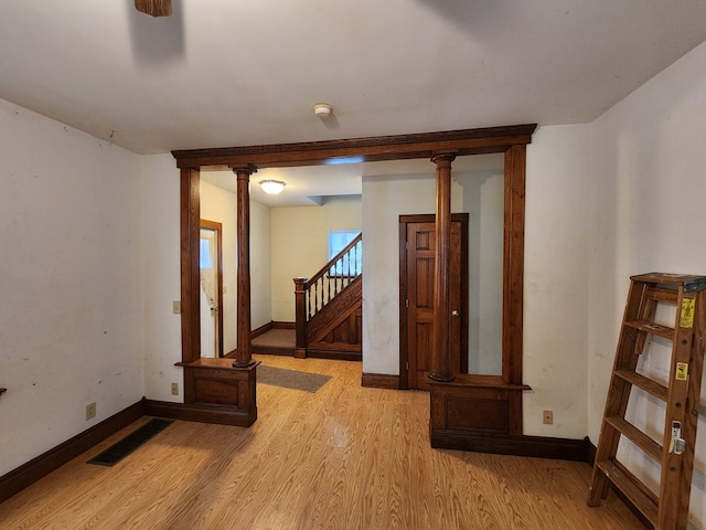 spare room with light hardwood / wood-style floors and ornate columns