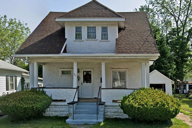 bungalow-style home with a porch, a garage, and an outdoor structure