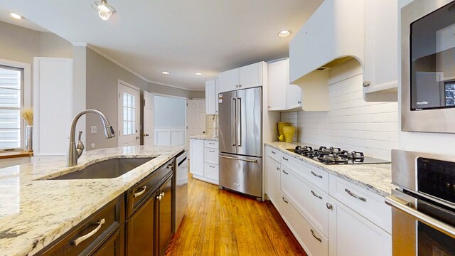 kitchen with white cabinetry, sink, light stone counters, and appliances with stainless steel finishes