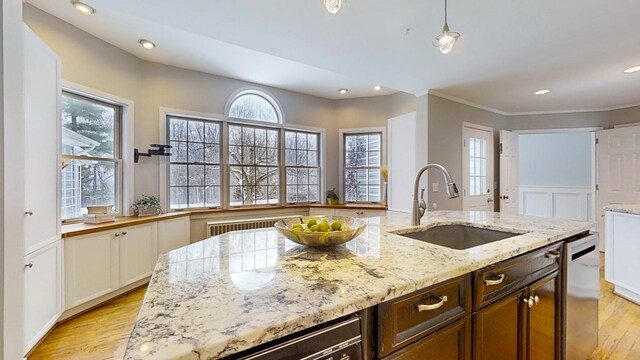 kitchen with white cabinetry, sink, stainless steel dishwasher, light stone counters, and light hardwood / wood-style floors