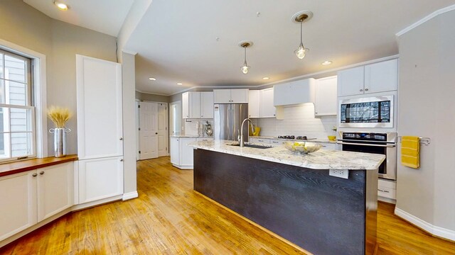 kitchen with pendant lighting, appliances with stainless steel finishes, light stone countertops, and white cabinets