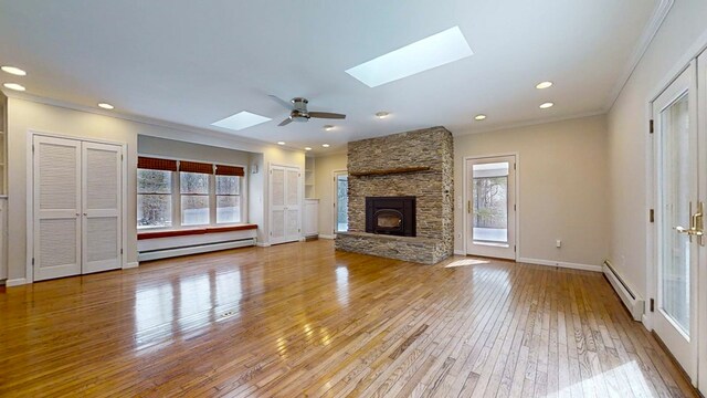 unfurnished living room with a baseboard radiator, a healthy amount of sunlight, and a skylight