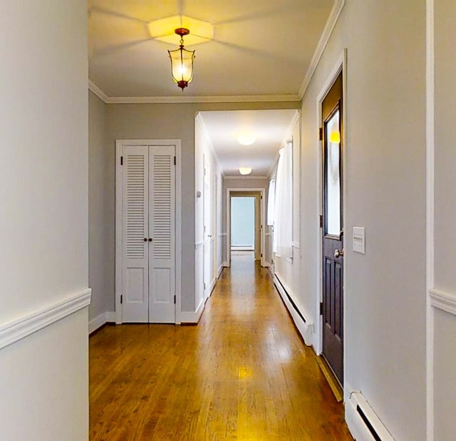 corridor with crown molding, a baseboard radiator, and hardwood / wood-style flooring