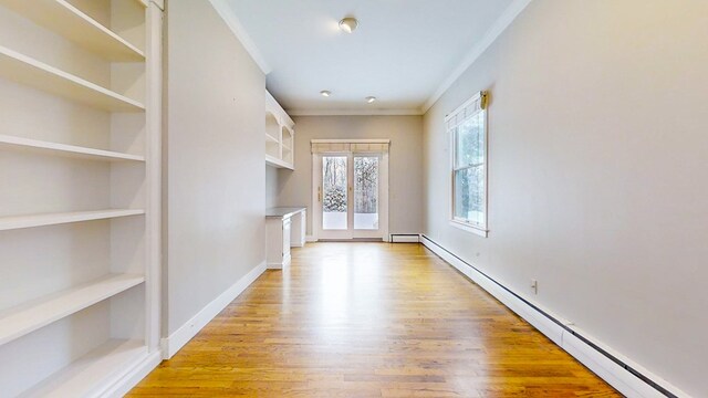 interior space featuring ornamental molding, a baseboard heating unit, built in features, and light hardwood / wood-style floors