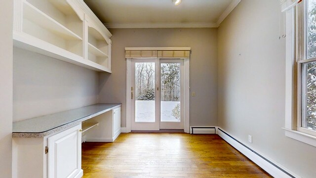 doorway to outside featuring built in desk, ornamental molding, light hardwood / wood-style floors, and baseboard heating