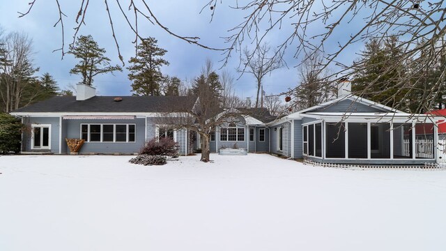 snow covered house featuring a sunroom