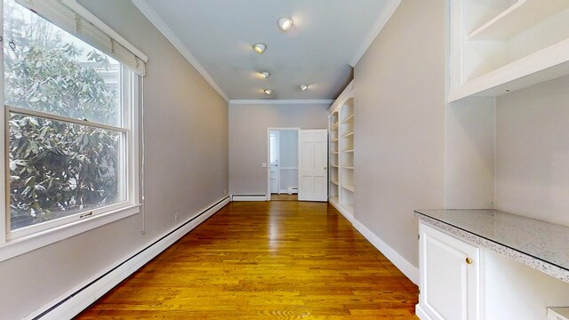 hallway featuring crown molding, hardwood / wood-style floors, and a baseboard heating unit