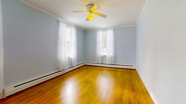 empty room with crown molding, ceiling fan, baseboard heating, and hardwood / wood-style floors