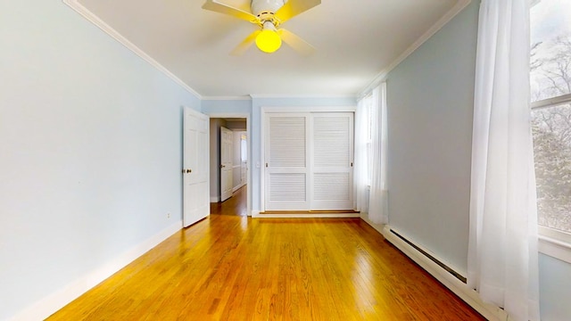 interior space featuring hardwood / wood-style flooring, ceiling fan, ornamental molding, and a baseboard heating unit