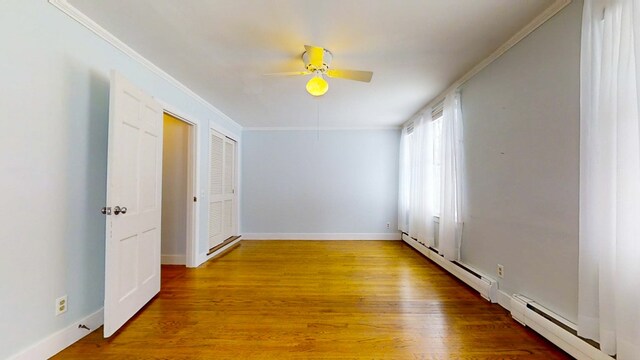 unfurnished room with wood-type flooring, ornamental molding, and baseboard heating