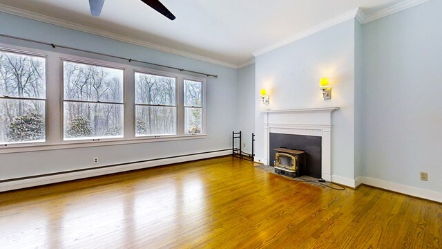 unfurnished living room featuring ceiling fan, wood-type flooring, ornamental molding, a baseboard radiator, and a wood stove