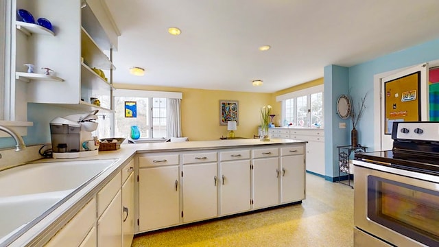 kitchen with white cabinetry, stainless steel electric range oven, and sink