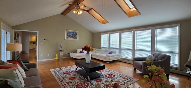 living room with ceiling fan, a skylight, high vaulted ceiling, beamed ceiling, and light wood-type flooring