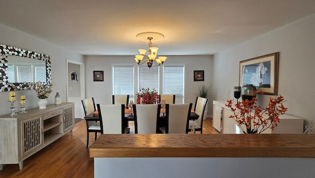 dining space with hardwood / wood-style floors and an inviting chandelier