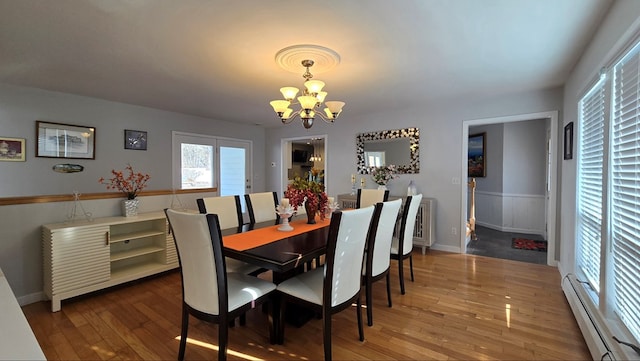 dining room featuring hardwood / wood-style flooring, a baseboard radiator, and a notable chandelier