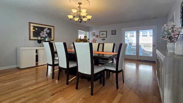 dining area with light hardwood / wood-style floors and a notable chandelier