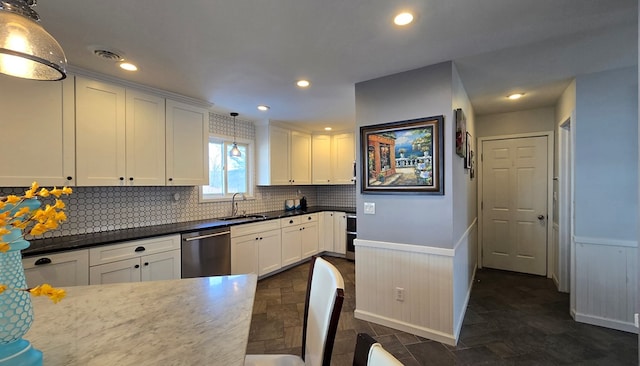 kitchen with tasteful backsplash, sink, white cabinets, hanging light fixtures, and stainless steel dishwasher