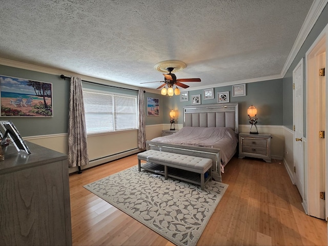 bedroom with crown molding, ceiling fan, a baseboard heating unit, a textured ceiling, and light wood-type flooring