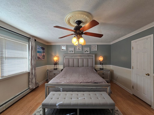 bedroom featuring crown molding, light hardwood / wood-style flooring, and a baseboard heating unit