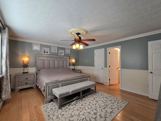 bedroom featuring crown molding, hardwood / wood-style floors, ceiling fan, and a textured ceiling