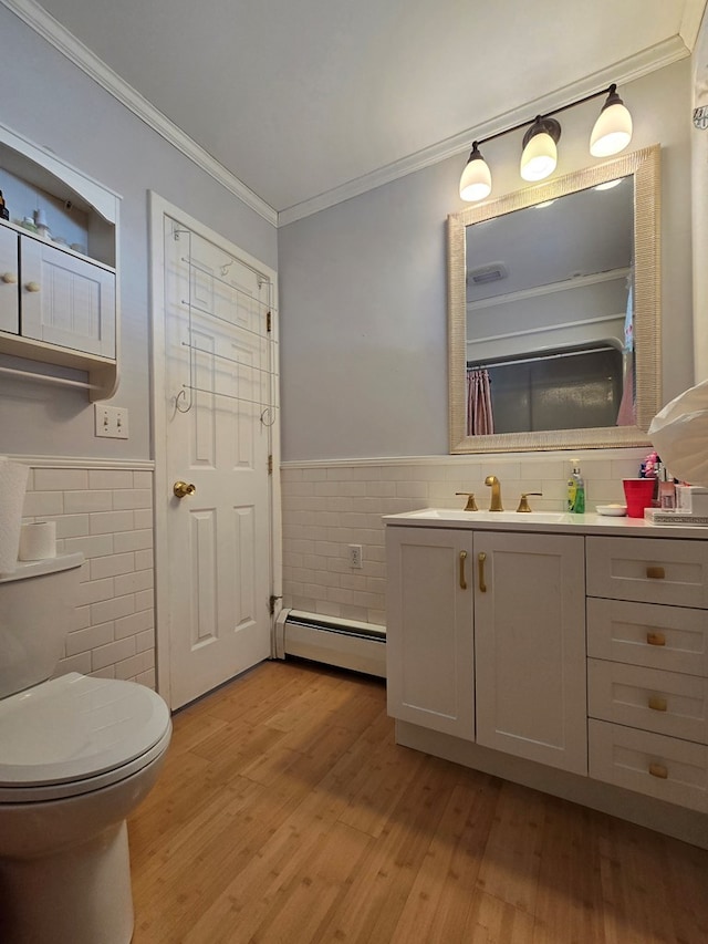 bathroom featuring toilet, wood-type flooring, baseboard heating, ornamental molding, and vanity