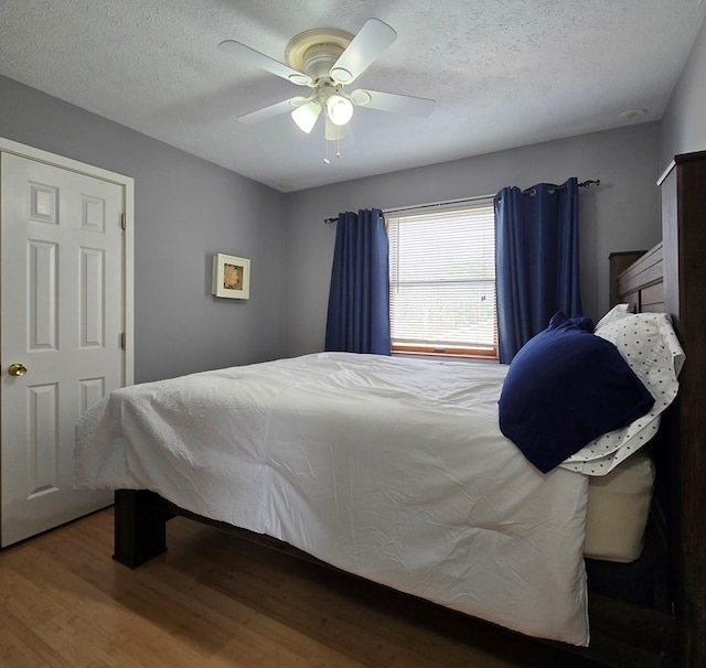 bedroom with ceiling fan, hardwood / wood-style floors, and a textured ceiling