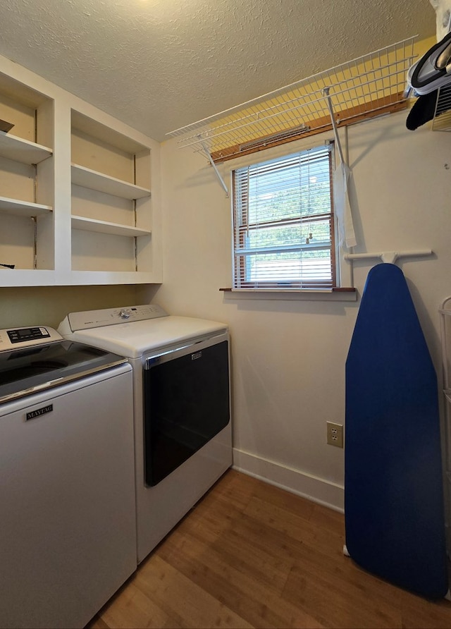 washroom with dark wood-type flooring, washing machine and clothes dryer, and a textured ceiling