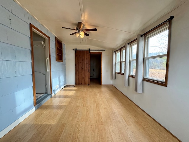 interior space with a barn door, lofted ceiling, and ceiling fan