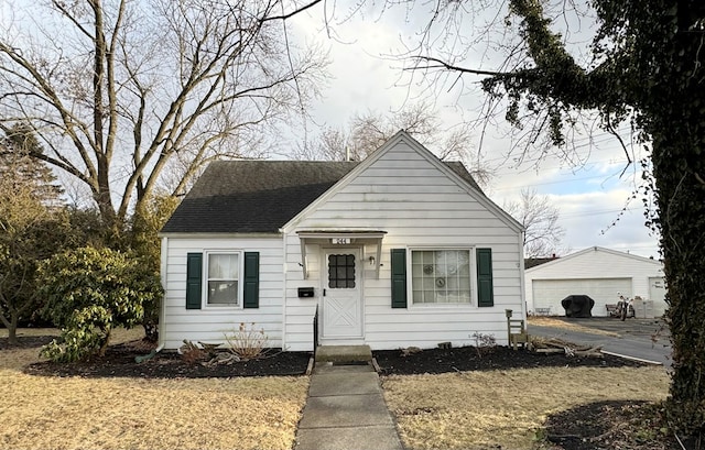 bungalow-style house featuring a garage, an outbuilding, and a front lawn