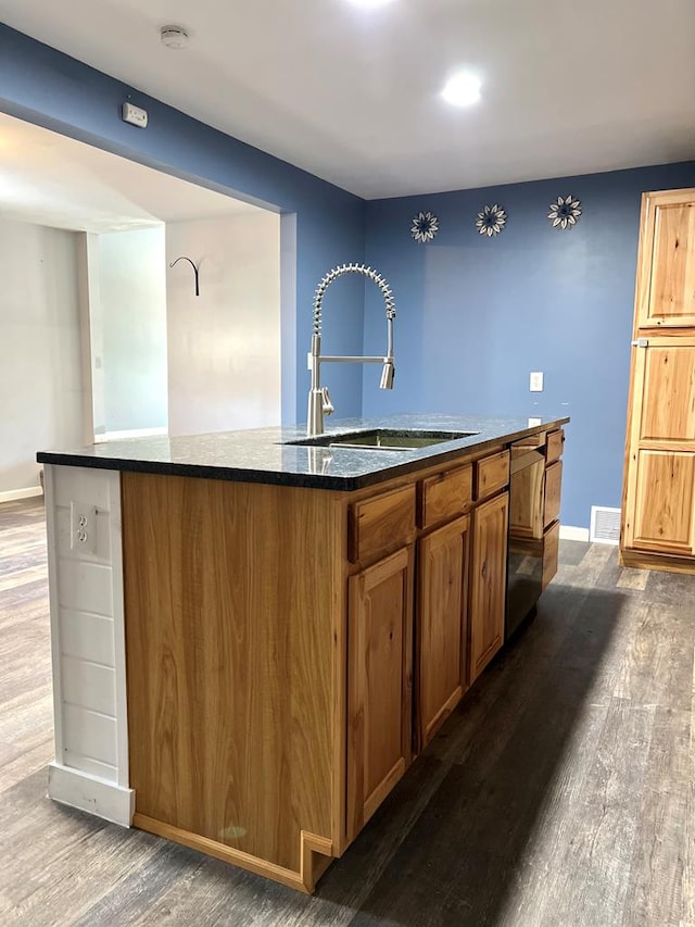 kitchen with dark hardwood / wood-style floors, stainless steel dishwasher, sink, and an island with sink