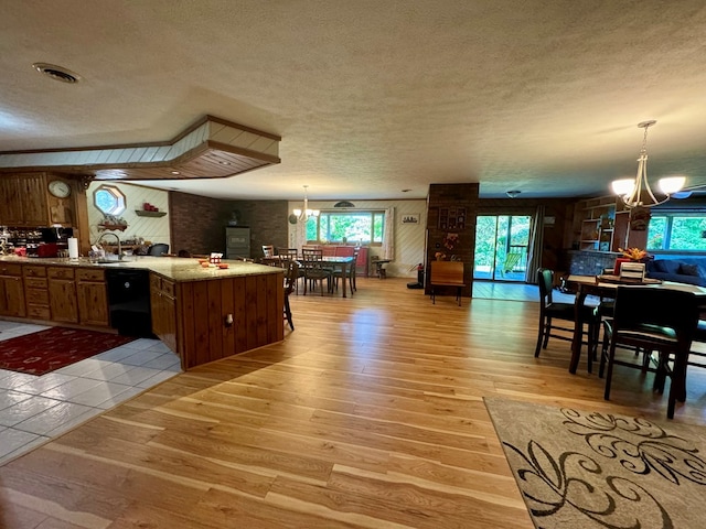 kitchen featuring dishwasher, pendant lighting, a notable chandelier, and light hardwood / wood-style floors