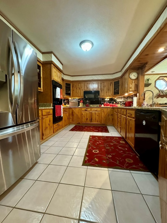 kitchen featuring sink, light tile patterned floors, and black appliances