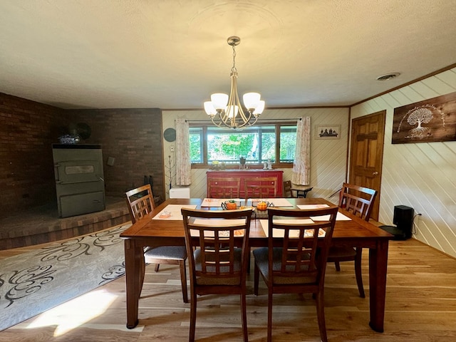 dining room with a wood stove, hardwood / wood-style floors, and a chandelier