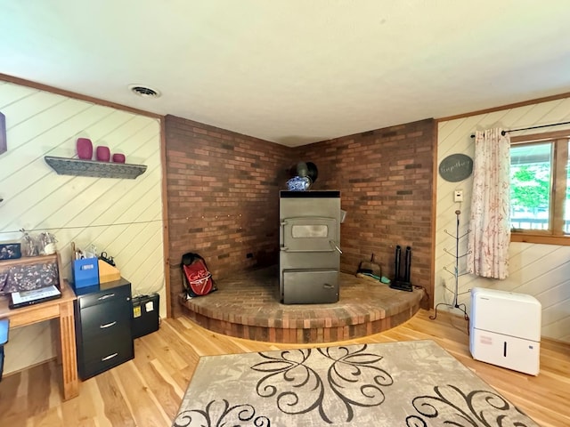 living room with crown molding, wood-type flooring, wooden walls, and a wood stove