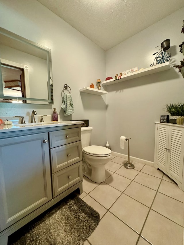 bathroom featuring tile patterned flooring, vanity, a textured ceiling, and toilet