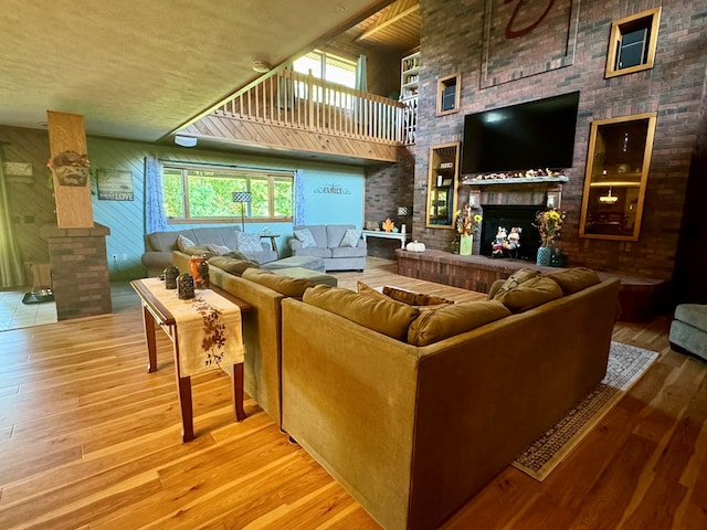 living room featuring a towering ceiling, a fireplace, and light wood-type flooring