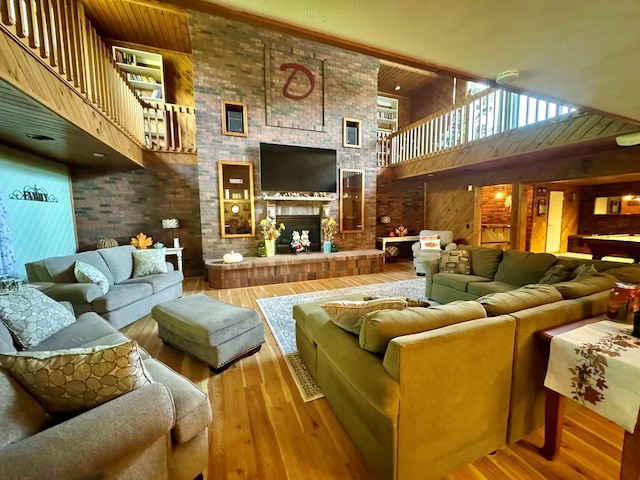 living room with wooden walls, a towering ceiling, a fireplace, and hardwood / wood-style floors