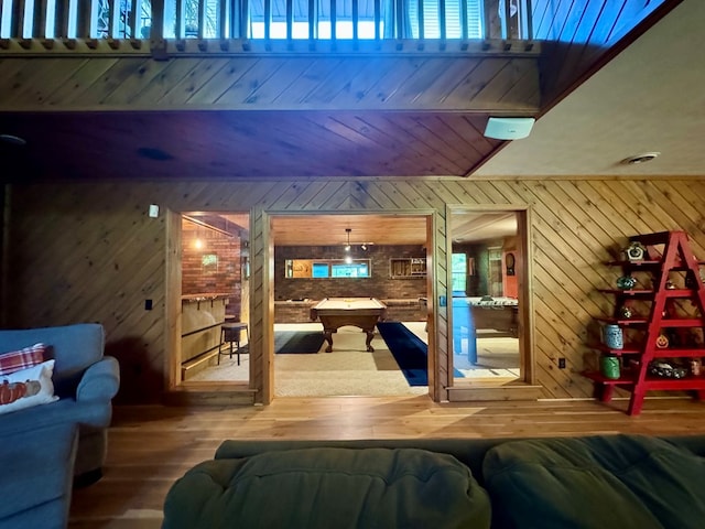 living room featuring hardwood / wood-style floors, pool table, and wood walls