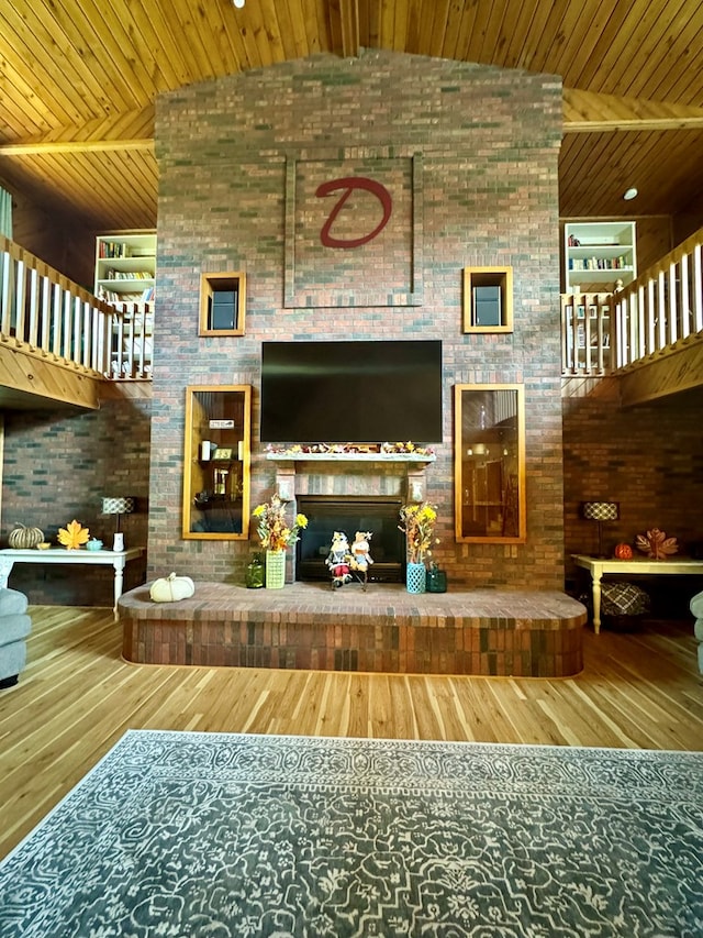 unfurnished living room featuring hardwood / wood-style floors, high vaulted ceiling, a fireplace, brick wall, and wooden ceiling