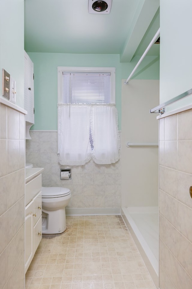 bathroom featuring tile walls, vanity, toilet, and walk in shower